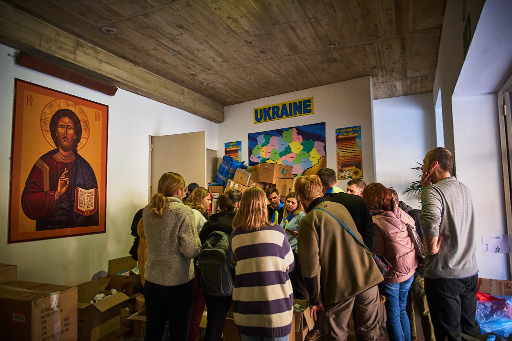 La comunitat ucraïnesa atura la recollida de queviures i material humanitari a la parròquia de Santa Mònica de la Rambla de Barcelona per escoltar el darrer butlletí de notícies que els arriba des del seu país.