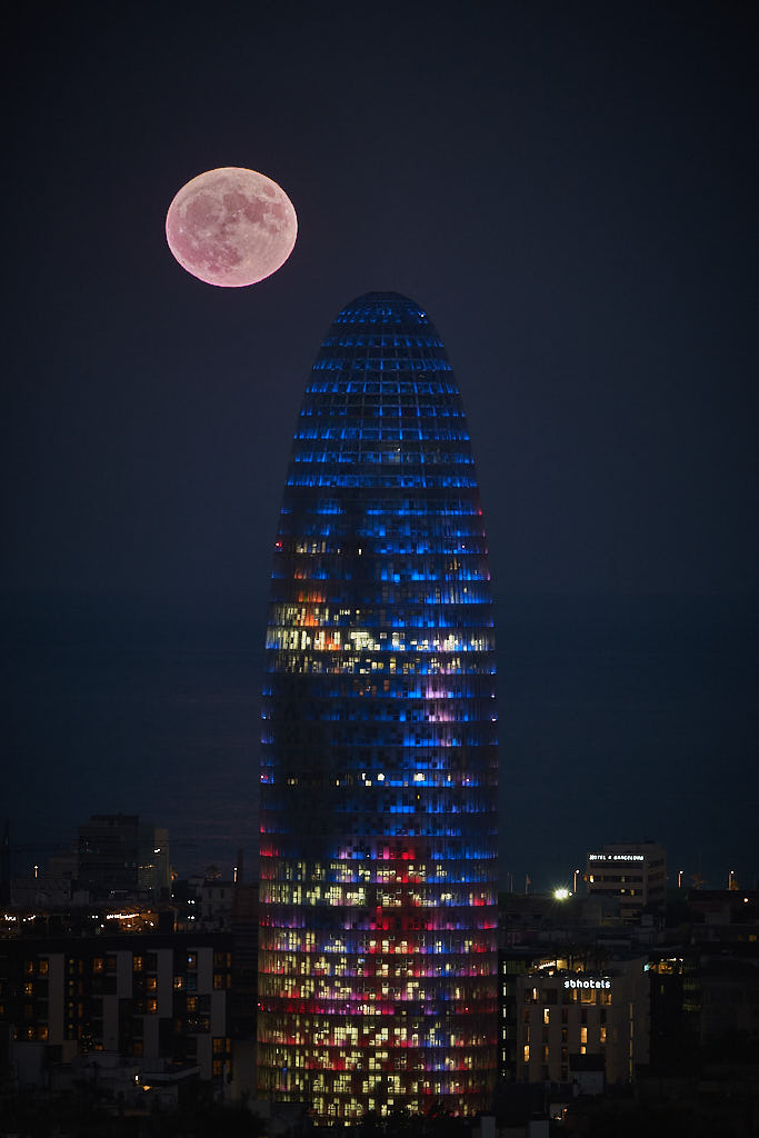 Lluna plena sobre Barcelona. En primer terme, la Torre Glòries, en el barri del Poblenou.
