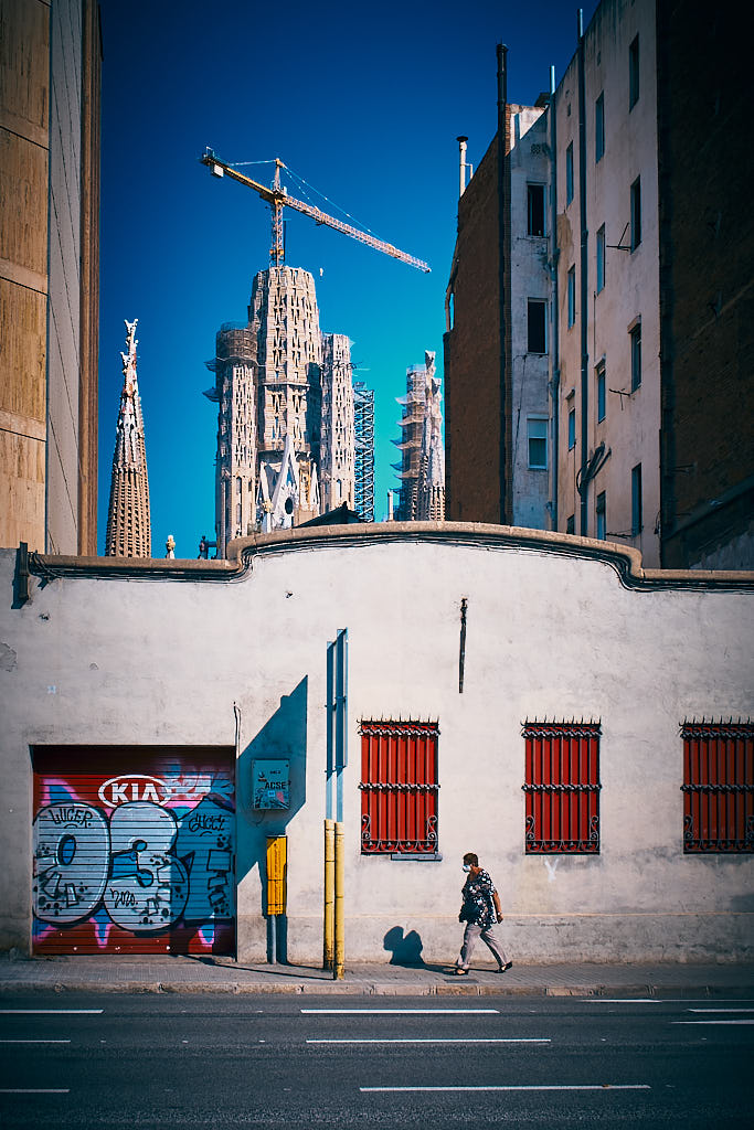 La Sagrada Família emergeix entre els edificis del carrer d'Aragó de Barcelona, a l'altura de la plaça de Pablo Neruda i de la confluència amb el carrer de Sardenya i la Diagonal.
