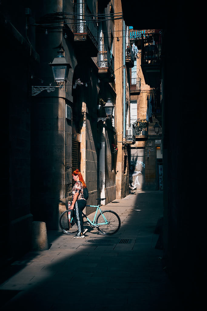 Una noia es passeja amb una bicleta a la mà pel carrer dels Mirallers, en el barri del Born de Barcelona.