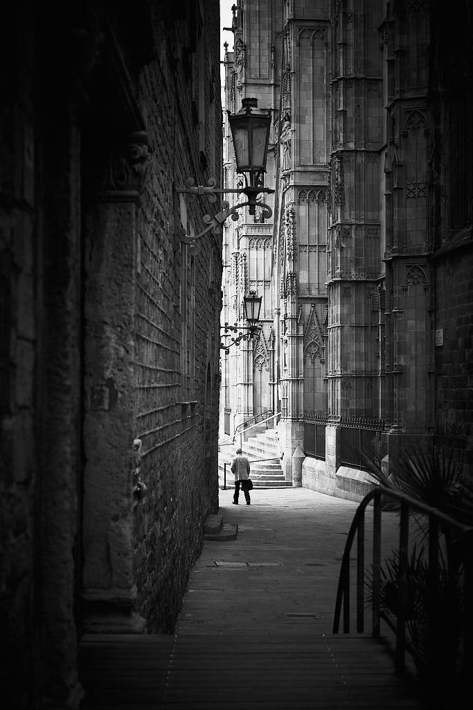 Un senyor camina pel carrer de Santa Llúcia, entre la Catedral de Barcelona i la Casa de l'Ardiaca.