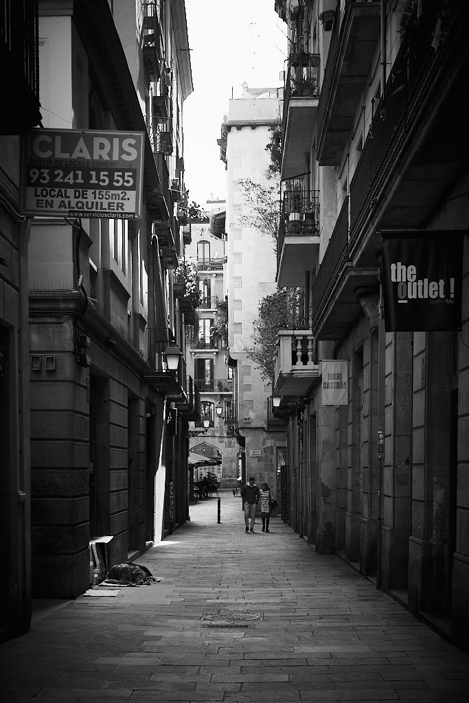 Couple walking through an alley of El Born, in the Old Town of Barcelona.