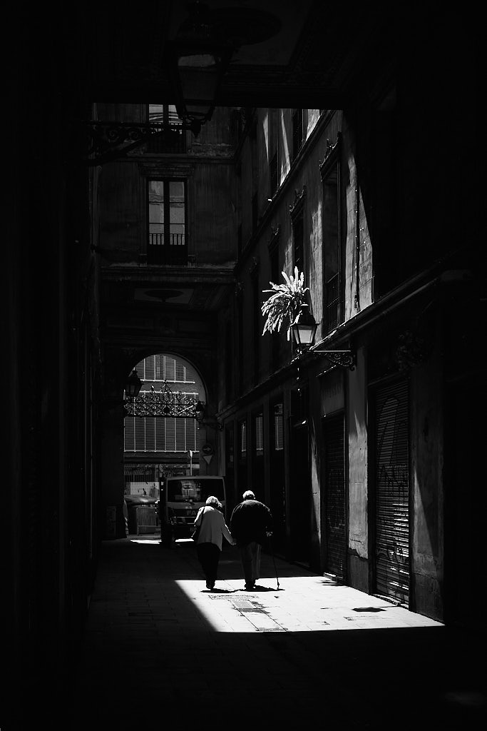 Old couple walking through a famous passage in the Gothic Quarter of Barcelona.
